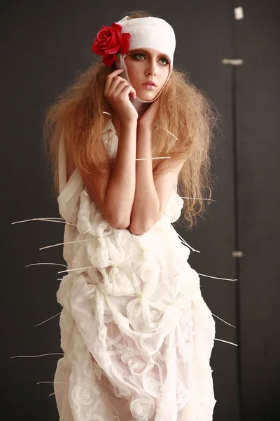 genç, kırılgan kız ayakta bir bornoz bandajlı bir kafa ile saçında hasta kırmızı çiçek