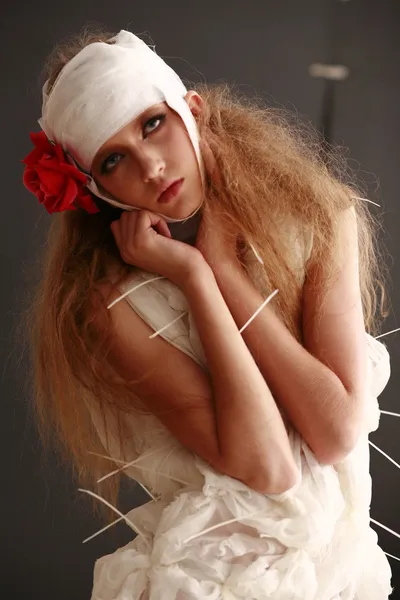 genç, kırılgan kız ayakta bir bornoz bandajlı bir kafa ile saçında hasta kırmızı çiçek