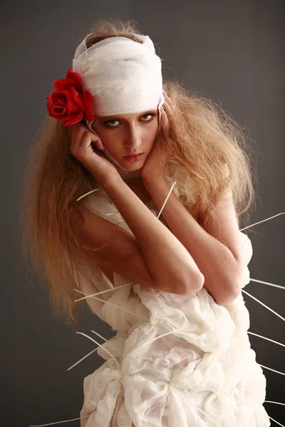 genç, kırılgan kız ayakta bir bornoz bandajlı bir kafa ile saçında hasta kırmızı çiçek