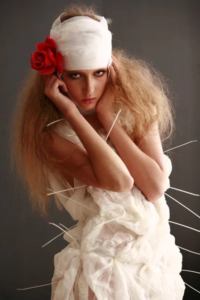 Young, fragile girl standing in a bathrobe with a bandaged head, sick red flower in her hair — Stock Photo, Image