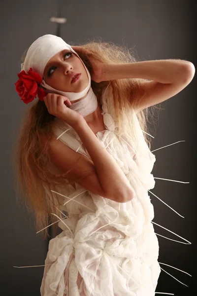 Young, fragile girl standing in a bathrobe with a bandaged head, sick red flower in her hair — Stock Photo, Image