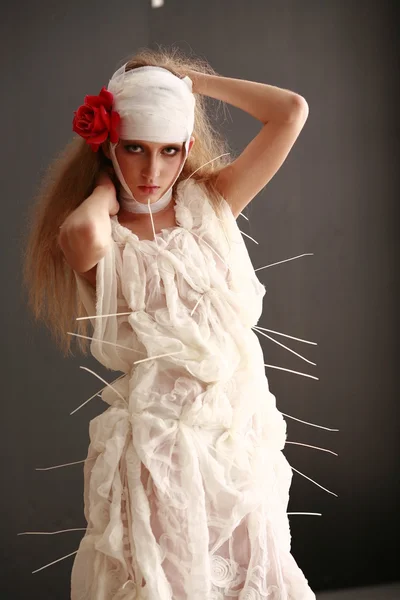 genç, kırılgan kız ayakta bir bornoz bandajlı bir kafa ile saçında hasta kırmızı çiçek