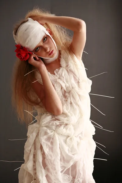 genç, kırılgan kız ayakta bir bornoz bandajlı bir kafa ile saçında hasta kırmızı çiçek