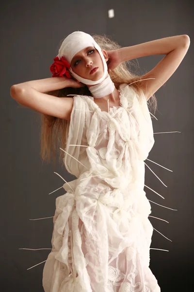 genç, kırılgan kız ayakta bir bornoz bandajlı bir kafa ile saçında hasta kırmızı çiçek