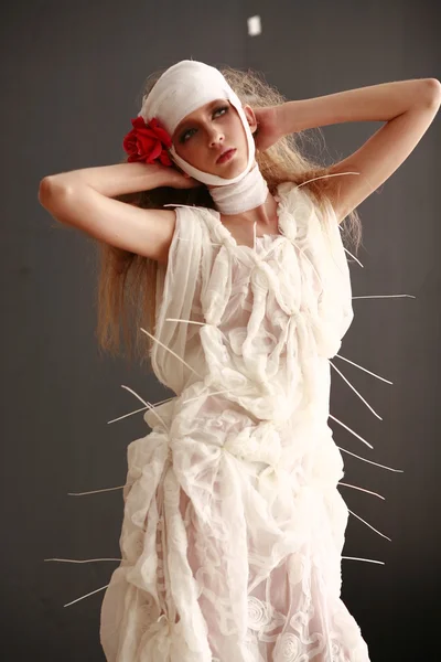 Jovem, menina frágil de pé em um roupão de banho com uma cabeça enfaixada, flor vermelha doente em seu cabelo — Fotografia de Stock