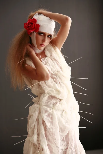 Young, fragile girl standing in a bathrobe with a bandaged head, sick red flower in her hair — Stock Photo, Image