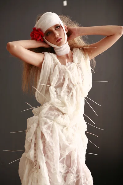 genç, kırılgan kız ayakta bir bornoz bandajlı bir kafa ile saçında hasta kırmızı çiçek