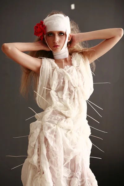 genç, kırılgan kız ayakta bir bornoz bandajlı bir kafa ile saçında hasta kırmızı çiçek