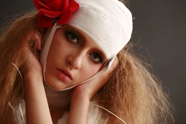 genç, kırılgan kız ayakta bir bornoz bandajlı bir kafa ile saçında hasta kırmızı çiçek