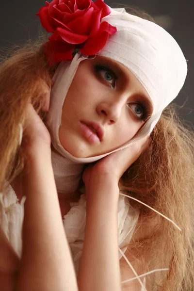 Mladá, křehká dívka stojící v županu s ovázanou hlavou, nemocný červená květina ve vlasech — Stock fotografie