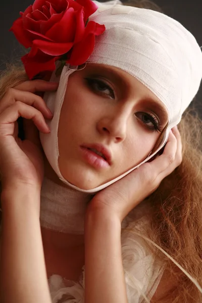 genç, kırılgan kız ayakta bir bornoz bandajlı bir kafa ile saçında hasta kırmızı çiçek