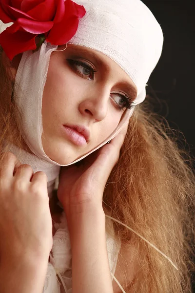 genç, kırılgan kız ayakta bir bornoz bandajlı bir kafa ile saçında hasta kırmızı çiçek