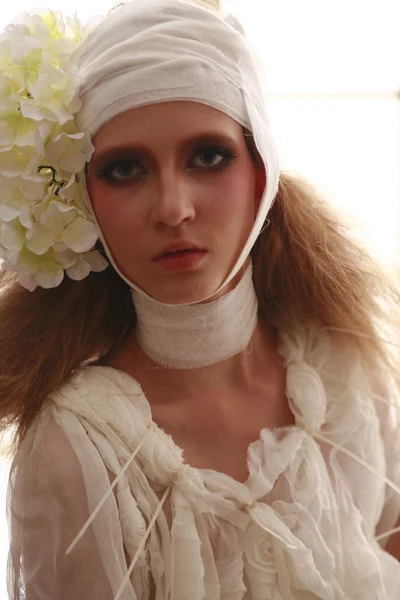 genç, kırılgan kız ayakta bir bornoz bandajlı bir kafa ile saçında hasta kırmızı çiçek