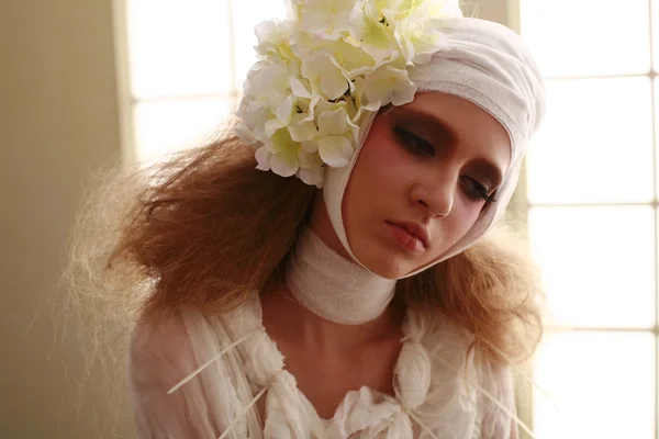 genç, kırılgan kız ayakta bir bornoz bandajlı bir kafa ile saçında hasta kırmızı çiçek