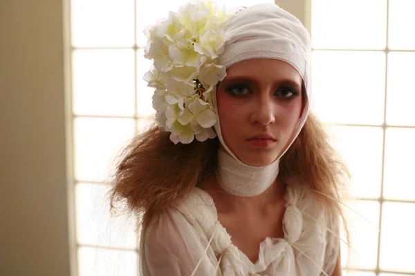 genç, kırılgan kız ayakta bir bornoz bandajlı bir kafa ile saçında hasta kırmızı çiçek