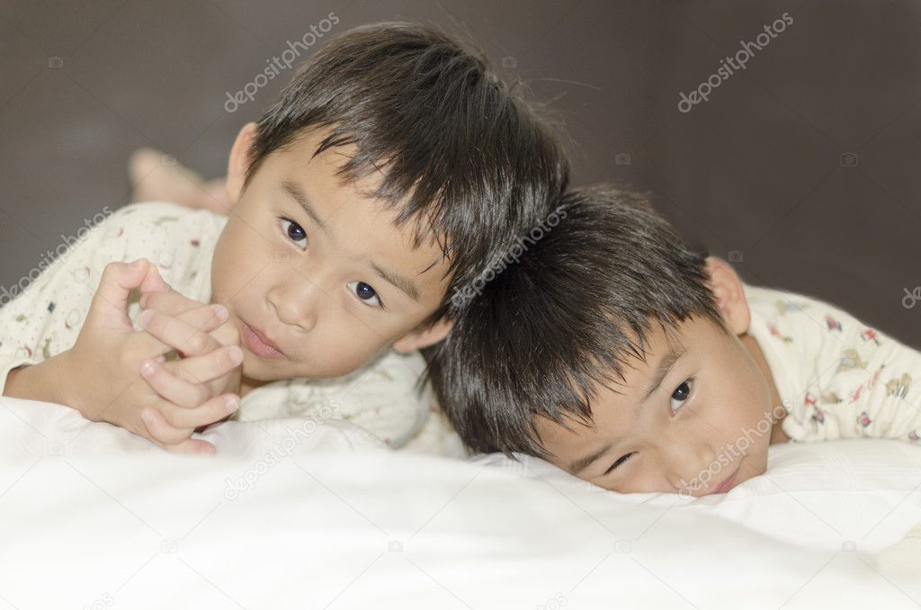 Two twins brothers lying on bed