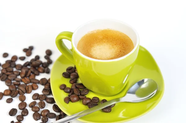 Yeşil espresso fincan kahve çekirdekleri ve kaşık ile