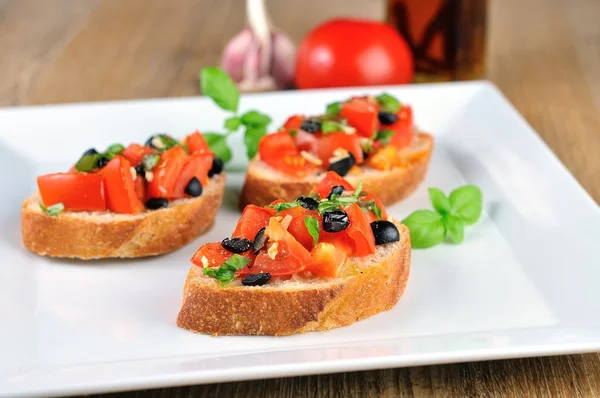 Bruschetta on wooden table and white plate — Stock Photo, Image