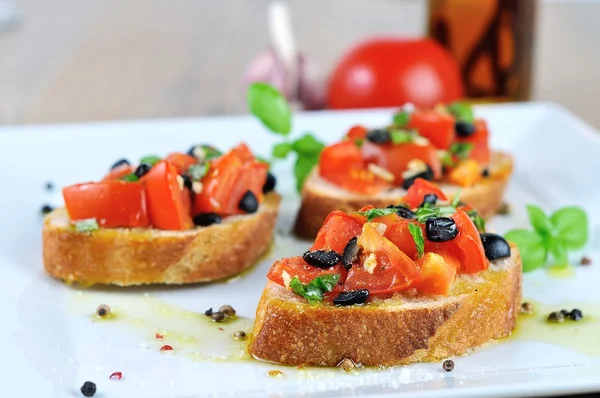 Bruschetta with oil on wooden table and white plate close up — Stock Photo, Image