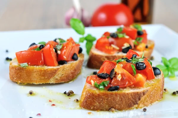 Färska bruschetta med olja på träbord och vita plattan stänga — Stockfoto