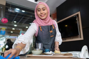 İş Dünyası Konsepti: Genç restoran garsonu müşteri için masa hazırlıyor