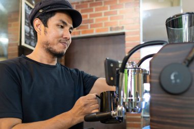 İş dünyası kavramı: Genç Malaylı barista makine kullanarak kahve hazırlıyor