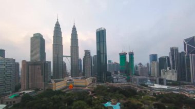 Kuala Lumpur, Malezya - 1 Şubat 2022: Petronas İkiz Kulesi 'nin (KLCC) ve günbatımı saatlerinde çevreleyen modern benzersiz yapısının hızlandırılmış görüntüleri