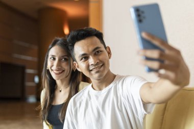 İlişki anı: Genç çift akıllı telefon kullanarak selfie çekiyor.