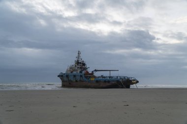 Kuantan, Pahang, Malezya - 9 Mart 2022 - Sabah bulutlu bir gündoğumuyla kıyıda mahsur kalan römorkör teknesi