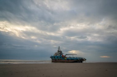 Kuantan, Pahang, Malezya - 9 Mart 2022 - Sabah bulutlu bir gündoğumuyla kıyıda mahsur kalan römorkör teknesi