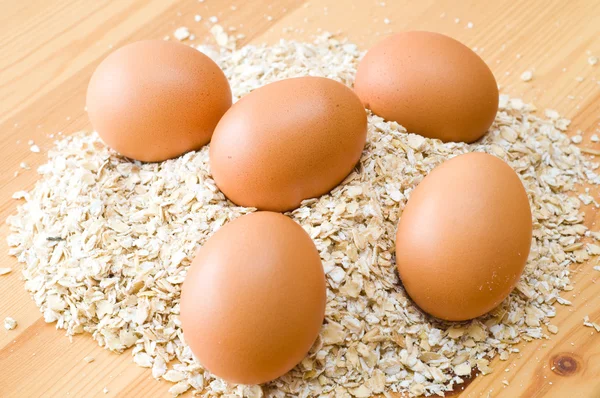Eier und Haferflocken auf Holztisch — Stockfoto