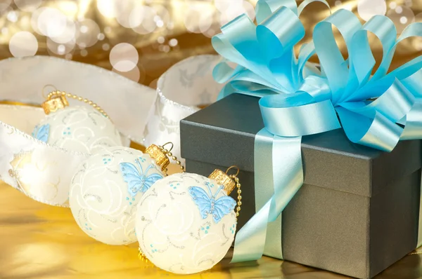 Gift boxes with blue ribbon and christmas toys on golden background — Stock Photo, Image