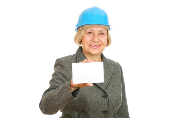 Mulher sênior com chapéu azul duro segurando um cartão em branco — Fotografia de Stock