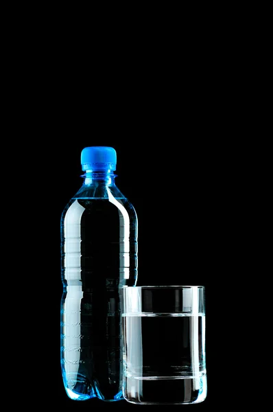 Bottled water and glass isolated on black background — Stock Photo, Image