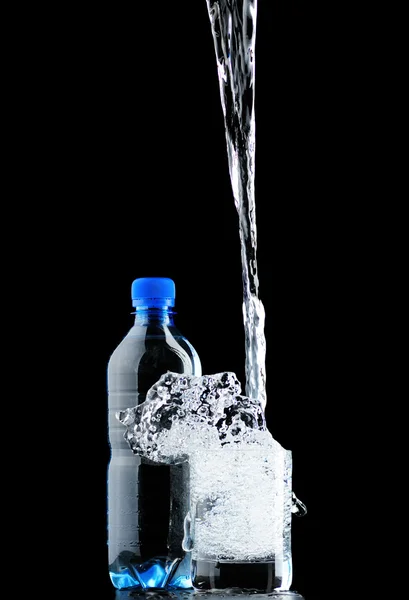 Vatten i glas och en flaska isolerad på svart bakgrund — Stockfoto