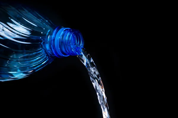 Pouring water from a bottle on black background — Stock Photo, Image