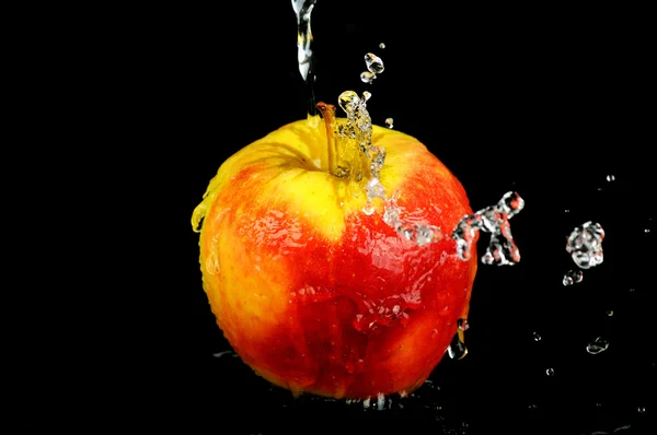 Sladké vody splash na červené jablko na černém pozadí — Stock fotografie