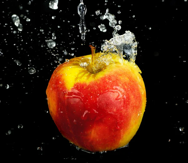 Plusk wody słodkiej na czerwone jabłko na czarnym tle — Zdjęcie stockowe