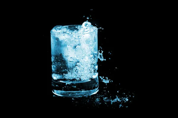 Gelo em vidro e respingo de água isolado sobre fundo preto — Fotografia de Stock