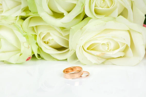 Rosas brancas e dois anéis de casamento dourados — Fotografia de Stock