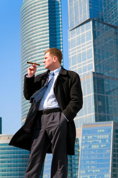 Affärsman med cigarr nära skyskrapor — Stockfoto
