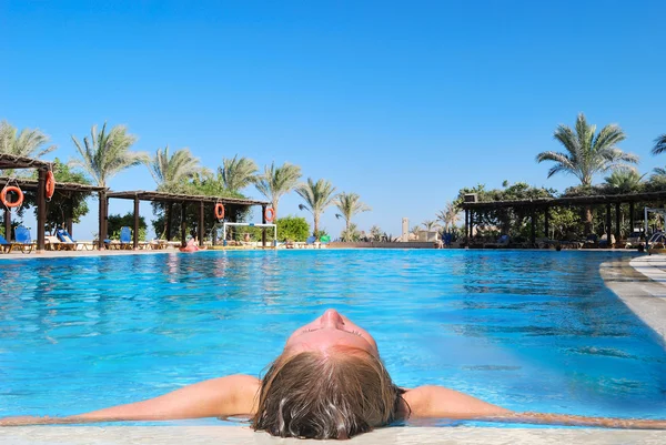 Vrouw ontspannen in blauwe zwembad buiten — Stockfoto