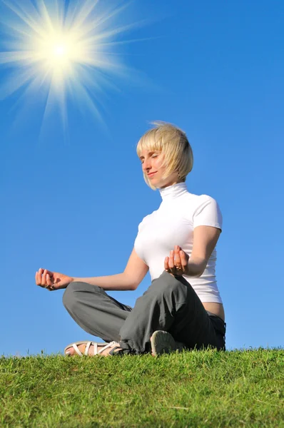 Genç kız meditasyon çayır üzerinde mavi gökyüzü — Stok fotoğraf