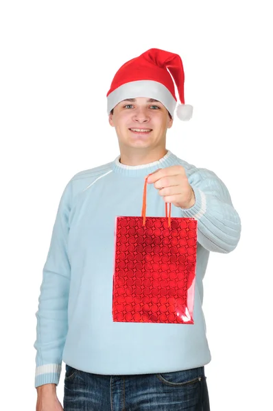 Młody człowiek w Świętego Mikołaja kapelusz gospodarstwa obecny torba na białym tle — Zdjęcie stockowe