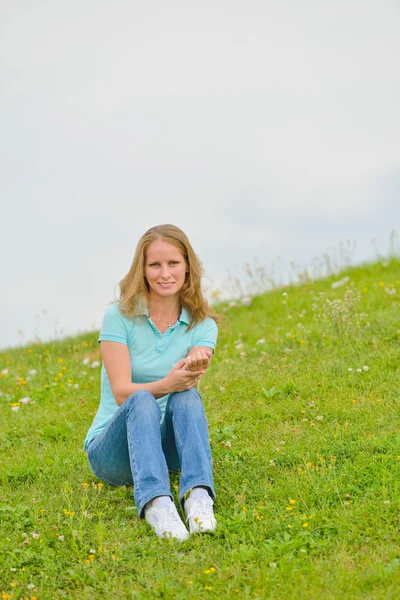 Jeune femme assise sur l'herbe — Photo