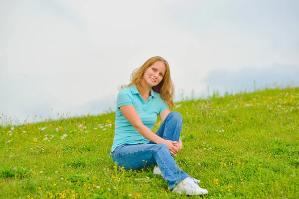 풀 위에 앉아 있는 젊은 여자 — 스톡 사진