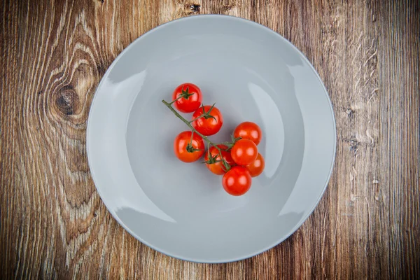 Cherry tomatoes on the plate on wooden table — Stock Photo, Image