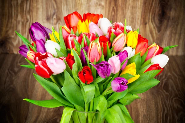 Tulips in the vase on wooden background — Stock Photo, Image