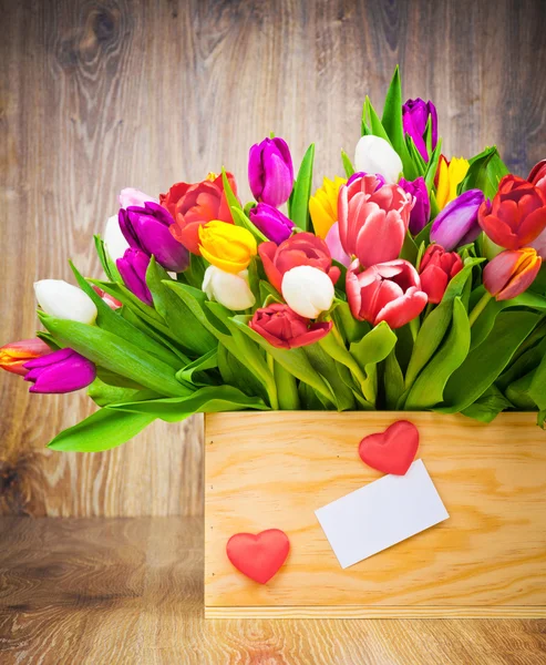 Tulipanes en la caja sobre fondo de madera — Foto de Stock