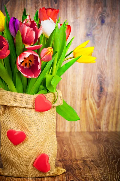 Tulpen in de zak op houten achtergrond — Stockfoto